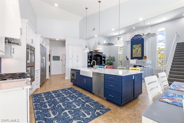 kitchen with an island with sink, blue cabinetry, hanging light fixtures, and stainless steel appliances