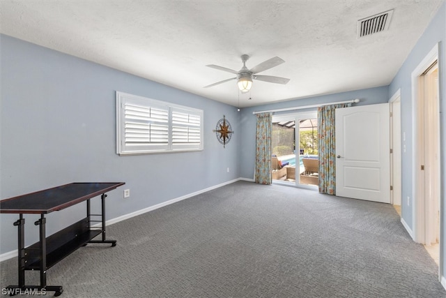 interior space featuring a textured ceiling, ceiling fan, and dark carpet