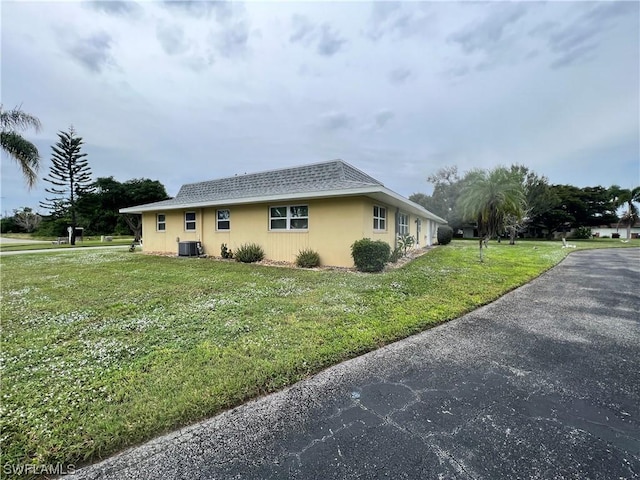 view of side of home with central AC unit and a yard