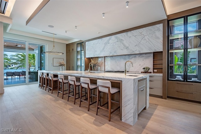 kitchen featuring a kitchen breakfast bar, a sink, light wood-style floors, modern cabinets, and a large island