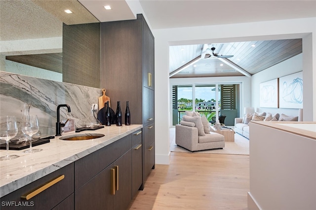 bar featuring tasteful backsplash, a sink, indoor wet bar, light wood finished floors, and recessed lighting