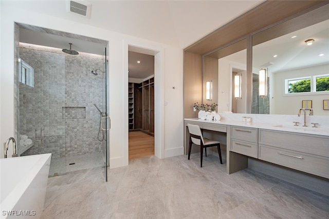 full bath with a shower stall, a walk in closet, vanity, a freestanding bath, and visible vents