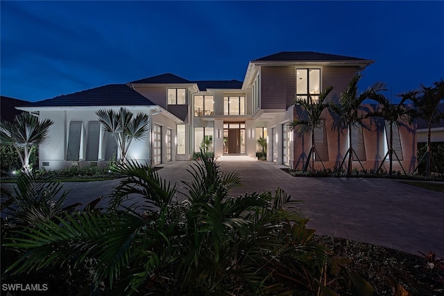 modern home with stucco siding, a balcony, and decorative driveway