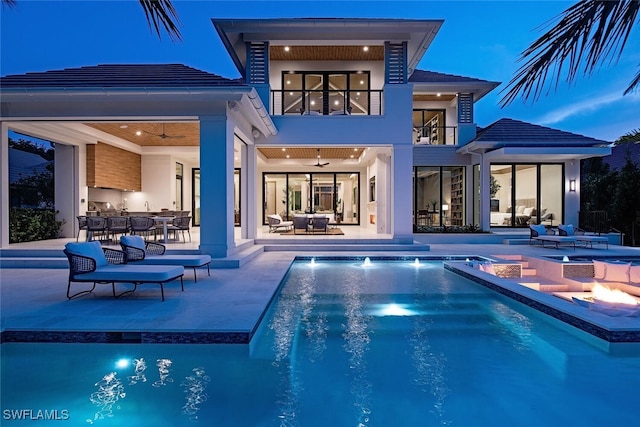 rear view of house with a patio area, a balcony, an outdoor pool, an outdoor kitchen, and ceiling fan