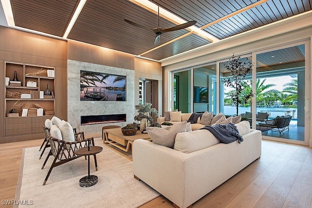living room with a high end fireplace, built in features, and wood finished floors