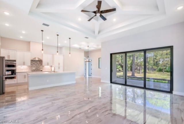 kitchen featuring light tile floors, hanging light fixtures, multiple ovens, tasteful backsplash, and white cabinetry