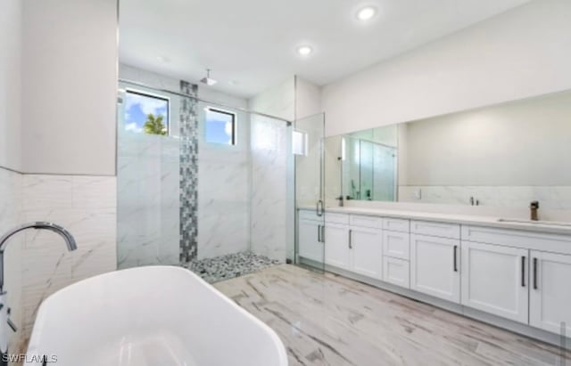 bathroom featuring tile walls, plus walk in shower, double sink, and large vanity