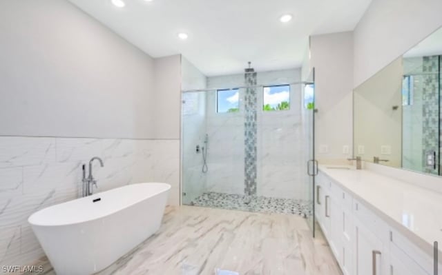 bathroom featuring tile walls, oversized vanity, and shower with separate bathtub