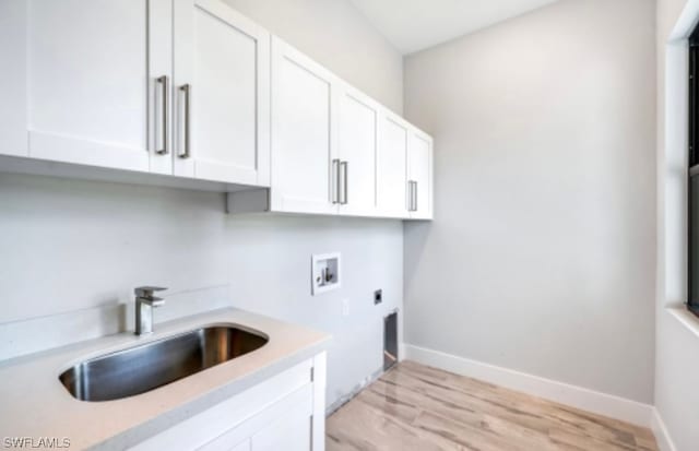 clothes washing area featuring cabinets, sink, light hardwood / wood-style flooring, electric dryer hookup, and hookup for a washing machine