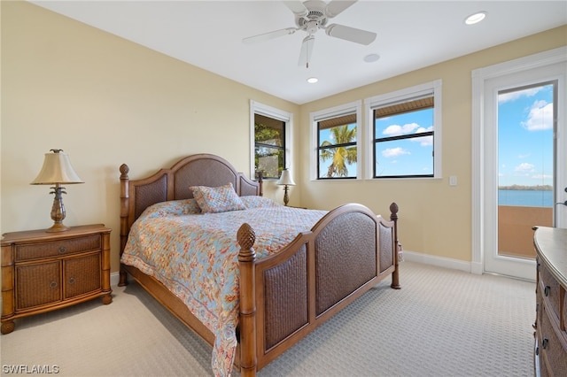 bedroom with light carpet, a water view, and ceiling fan