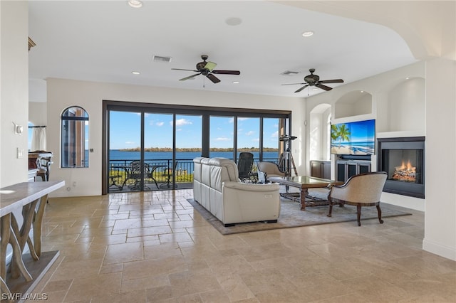 tiled living room with ceiling fan and a water view