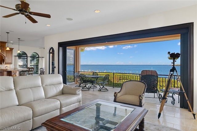 living room with light tile floors, ceiling fan, and a water view