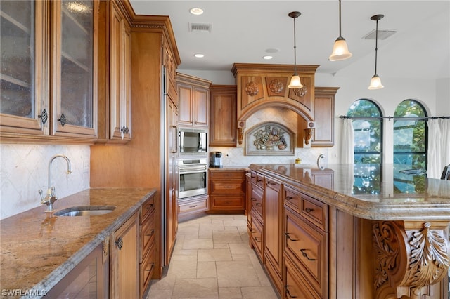 kitchen with backsplash, light stone counters, appliances with stainless steel finishes, and sink