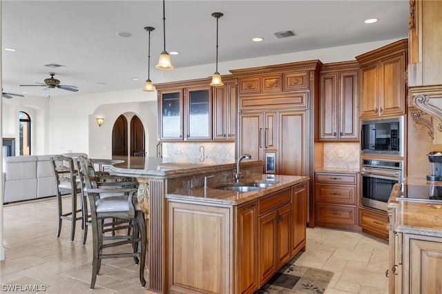 kitchen featuring a kitchen breakfast bar, built in appliances, tasteful backsplash, and ceiling fan