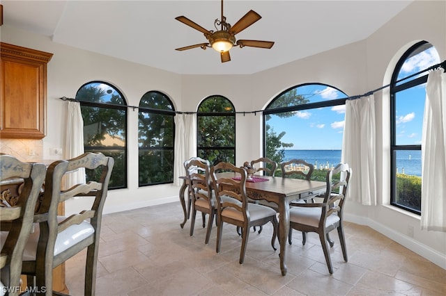 tiled dining area with plenty of natural light, ceiling fan, and a water view