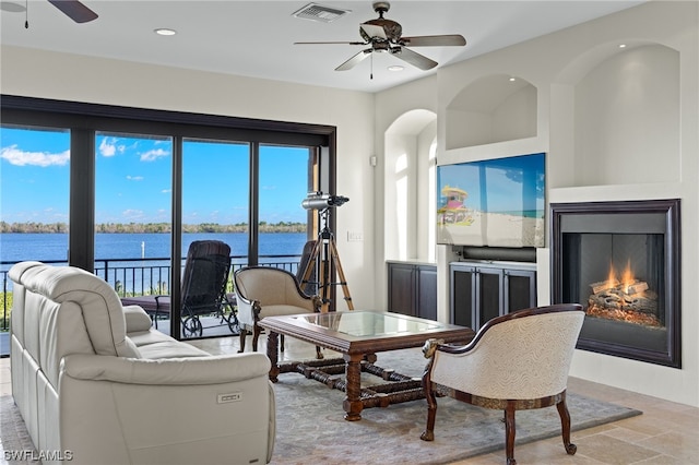 living room featuring light tile floors, ceiling fan, and a water view