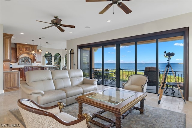 tiled living room featuring ceiling fan and a water view