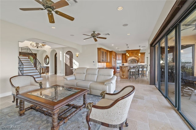 living room with a wealth of natural light, light tile floors, and ceiling fan with notable chandelier