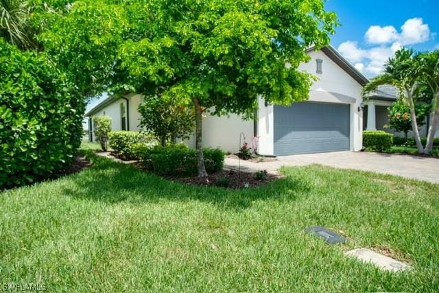 view of front of home with driveway, an attached garage, a front yard, and stucco siding