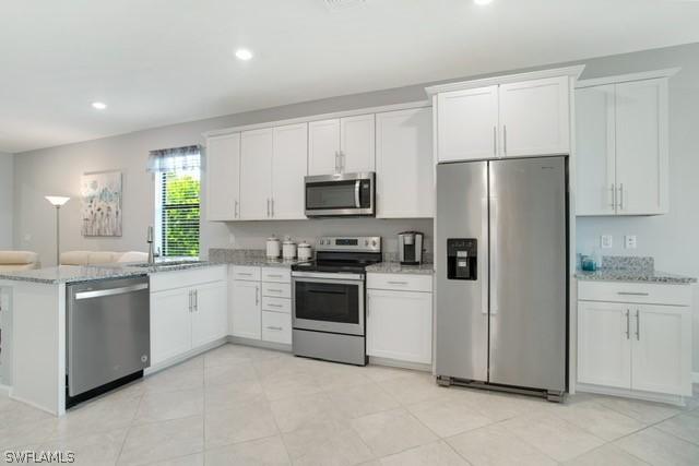 kitchen featuring stainless steel appliances, white cabinetry, a sink, and a peninsula