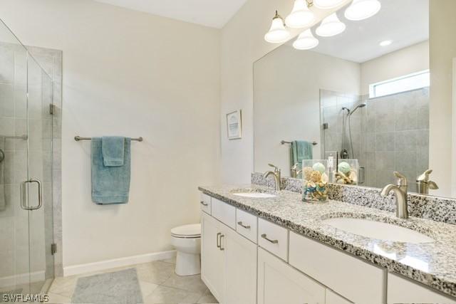 bathroom with double vanity, a stall shower, toilet, and a sink