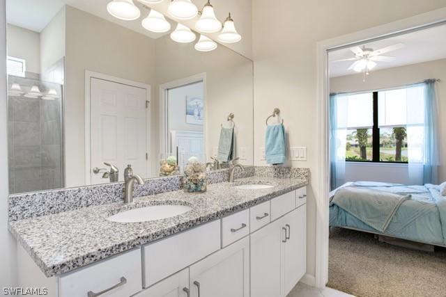 ensuite bathroom featuring a sink, double vanity, tiled shower, and connected bathroom