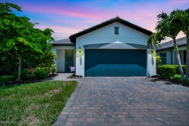 ranch-style house featuring decorative driveway, an attached garage, and stucco siding