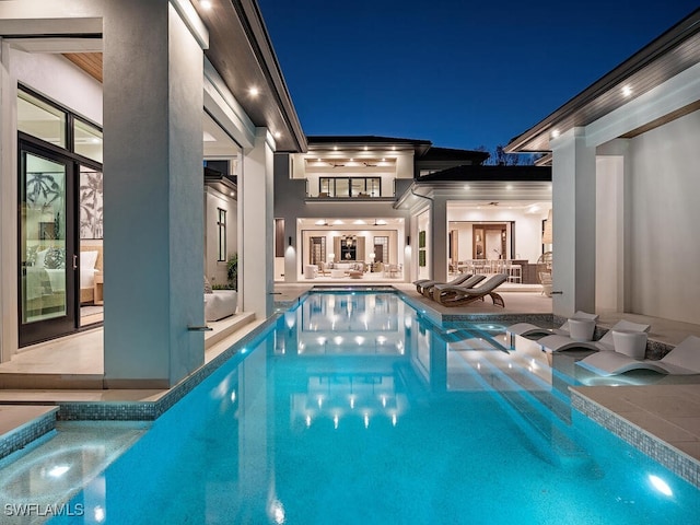 pool at night featuring a patio and an in ground hot tub