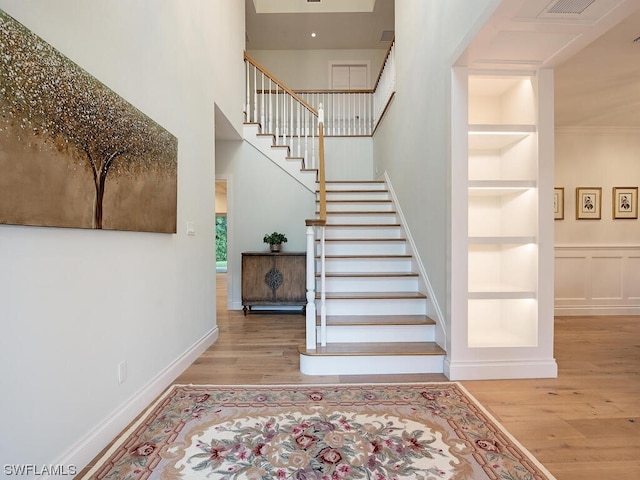 staircase with built in shelves and hardwood / wood-style floors