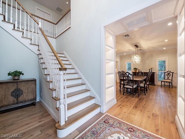 staircase featuring wood-type flooring and a notable chandelier
