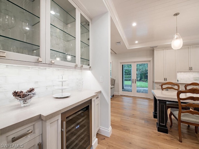 bar featuring pendant lighting, white cabinets, wine cooler, light hardwood / wood-style flooring, and tasteful backsplash