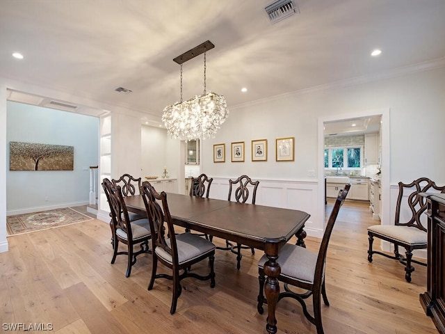 dining area featuring a chandelier, light wood-type flooring, and ornamental molding