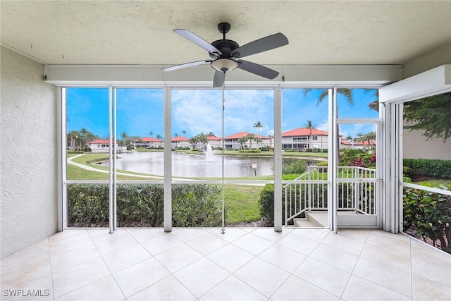 unfurnished sunroom with a water view and ceiling fan