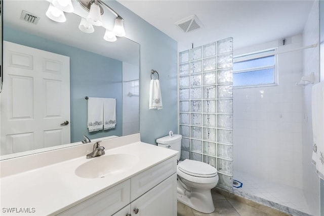 bathroom with tile patterned flooring, vanity, tiled shower, and toilet