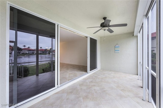 unfurnished sunroom featuring ceiling fan and a healthy amount of sunlight