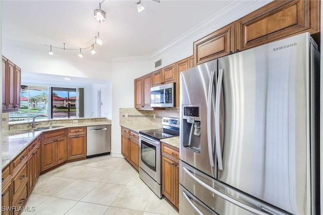 kitchen featuring sink, light tile patterned floors, stainless steel appliances, light stone counters, and ornamental molding