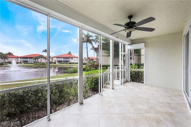 unfurnished sunroom with a water view and ceiling fan