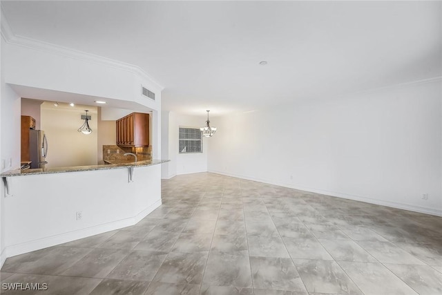 unfurnished living room featuring crown molding and a notable chandelier