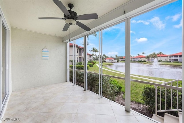 unfurnished sunroom with a water view and ceiling fan