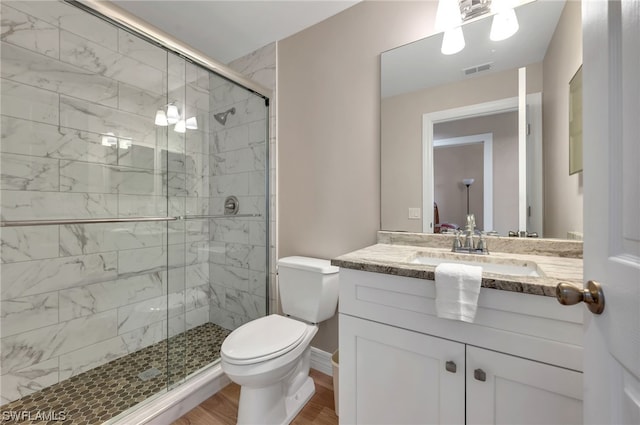 bathroom featuring wood-type flooring, vanity, toilet, and a shower with shower door