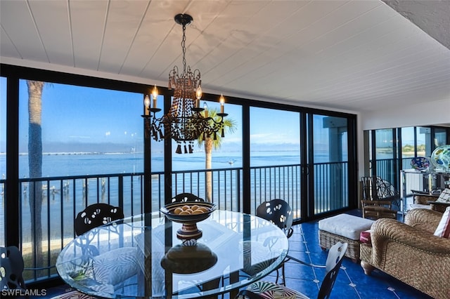 sunroom featuring an inviting chandelier and a water view