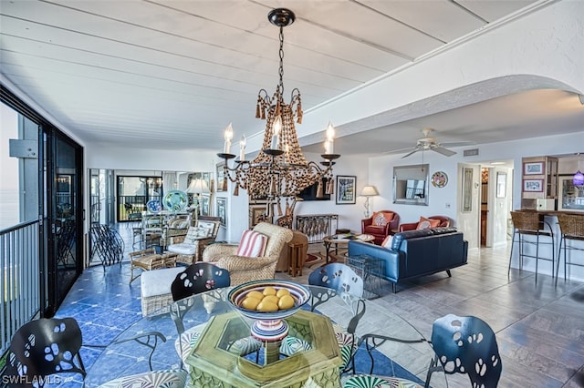 dining space with ceiling fan with notable chandelier and dark tile floors