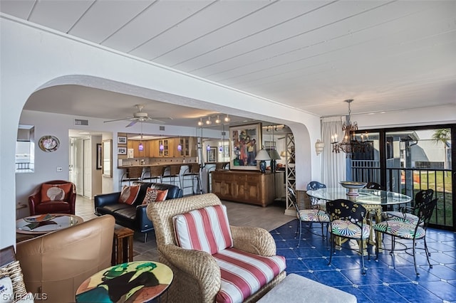 living room featuring dark tile flooring and ceiling fan with notable chandelier