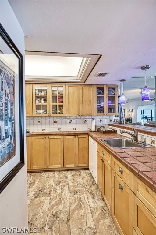 kitchen with white dishwasher, light tile floors, decorative light fixtures, backsplash, and sink