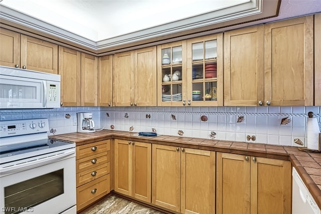 kitchen featuring white appliances, tasteful backsplash, tile countertops, and light wood-type flooring