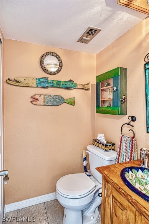 bathroom with toilet, vanity, and tile flooring