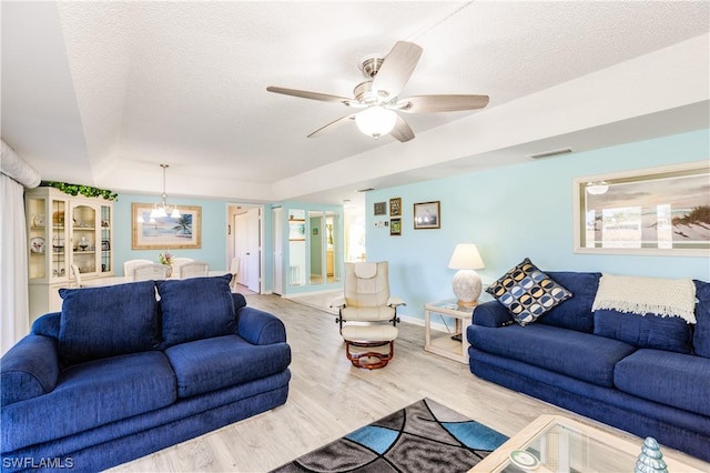 living room featuring ceiling fan, a textured ceiling, and light wood-type flooring