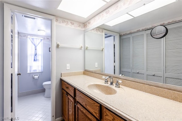 bathroom with vanity, toilet, a skylight, and tile patterned flooring