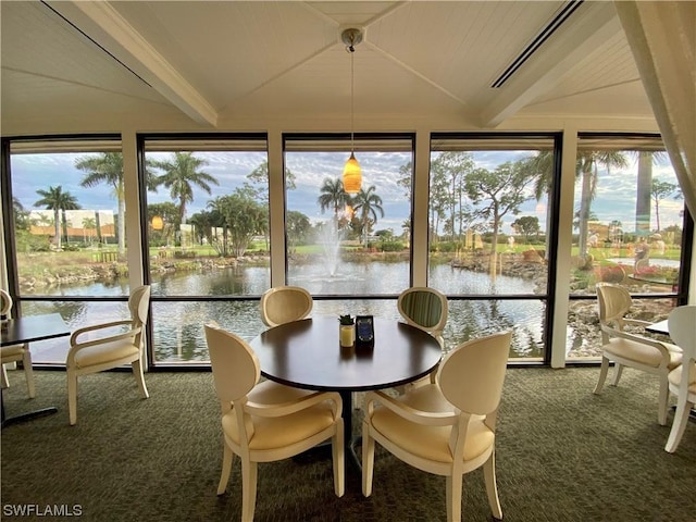 sunroom / solarium featuring a water view and vaulted ceiling with beams