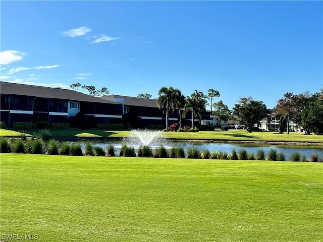 view of home's community with a water view and a lawn